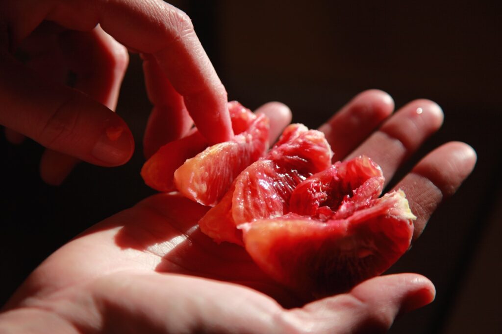person holding red sliced fruit
