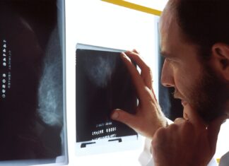 Back Exam person holding black tablet computer