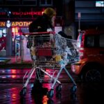 woman in black jacket riding red and silver shopping cart